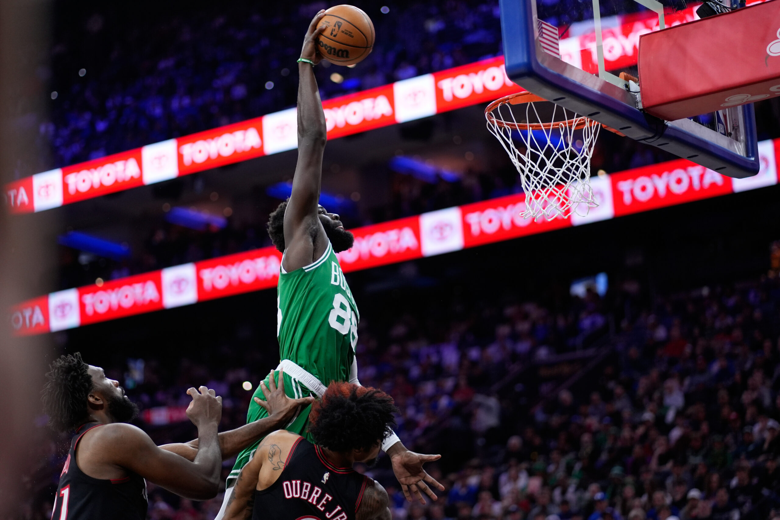 Neemias Queta, do Boston Celtics, no topo, sobe para uma enterrada sobre Kelly Oubre Jr., do Philadelphia 76ers, à direita, e Joel Embiid durante a primeira metade do jogo 4 em uma primeira rodada de basquete da NBA