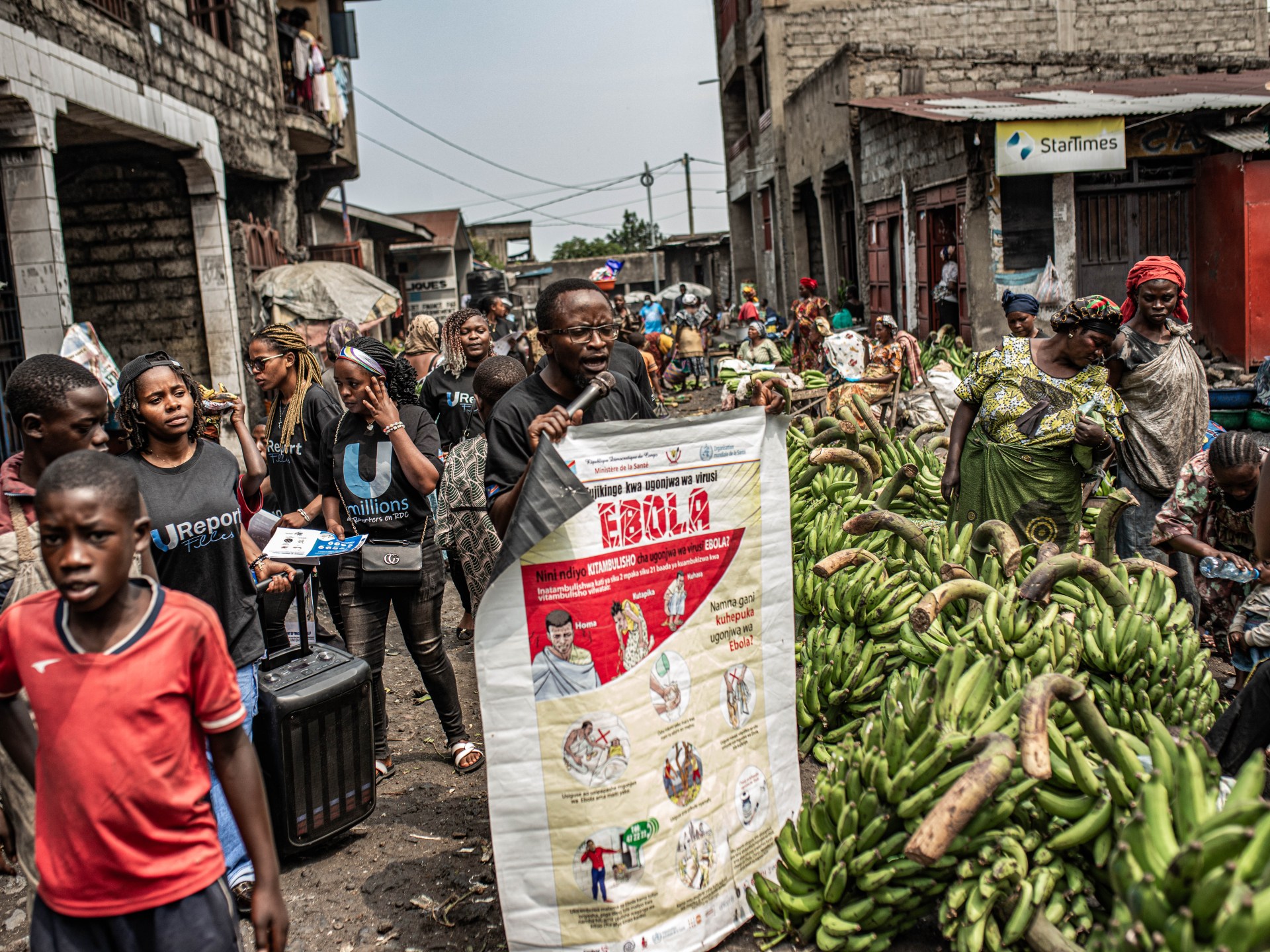 GOMA, REPÚBLICA DEMOCRÁTICA DO CONGO - 24 DE JUNHO: Uma mulher carregando bananas lê um panfleto enquanto trabalhadores do grupo 'U-Report' da UNICEF aumentam a conscientização sobre a transmissão do Ebola no mercado de Alanina em 24 de junho de 2026 em Goma, República Democrática do Congo. Na segunda-feira, as agências da ONU anunciaram que os casos de Ébola na República Democrática do Congo ultrapassaram os 1.000. Embora a capacidade de testagem tenha melhorado recentemente, a vigilância e o rastreio de contactos continuam limitados pela insegurança e pelo acesso restrito na província de Ituri, o centro do actual surto, a norte de Goma. (Foto de Daniel Buuma/Getty Images)