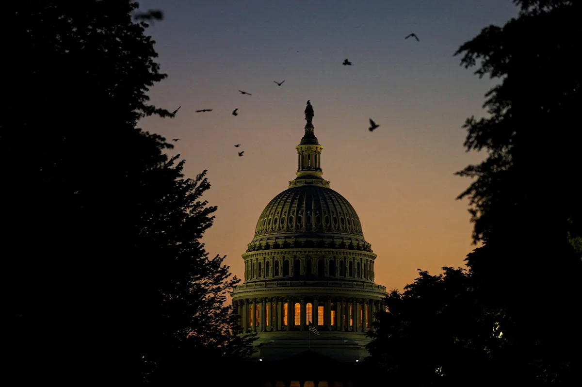 Os pássaros voam entre as árvores enquanto o sol se põe perto do Capitólio dos EUA em Washington, DC, 13 de julho de 2026.