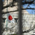a Japanese flag fluttering in the wind in the distance in front of a building in Tokyo