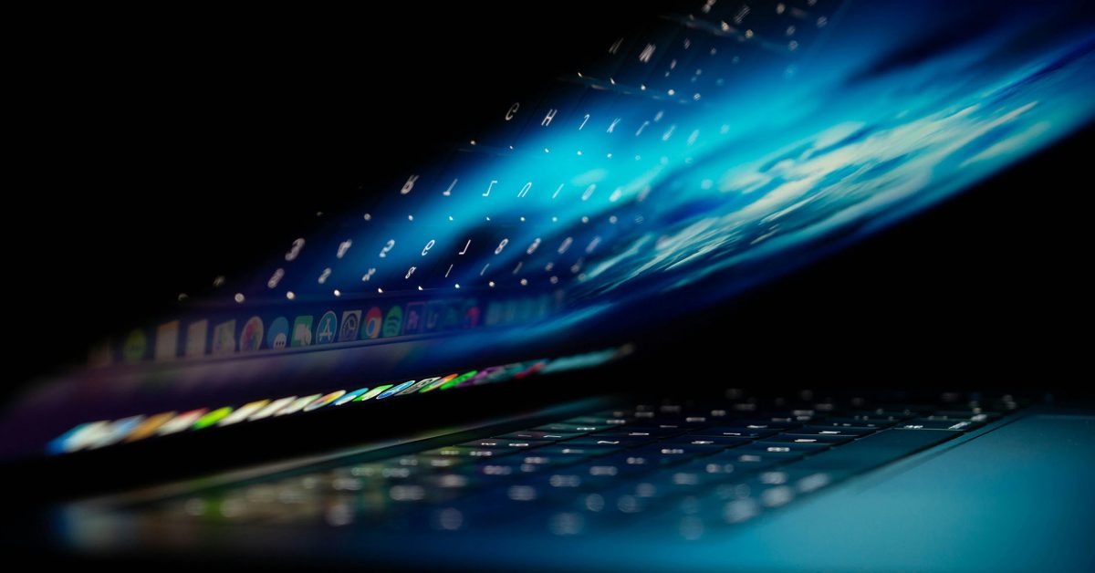 Cuidado com relatórios falsos de falhas do Mac | A imagem mostra um MacBook parcialmente aberto com gráficos abstratos em azul