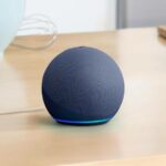 Alto-falante inteligente Amazon Echo branco em uma superfície de madeira com alguns ícones de habilidades do Alexa flutuando acima dele.