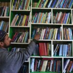 Um homem lê um livro dentro de uma biblioteca em Srinagar, 17 de fevereiro de 2025