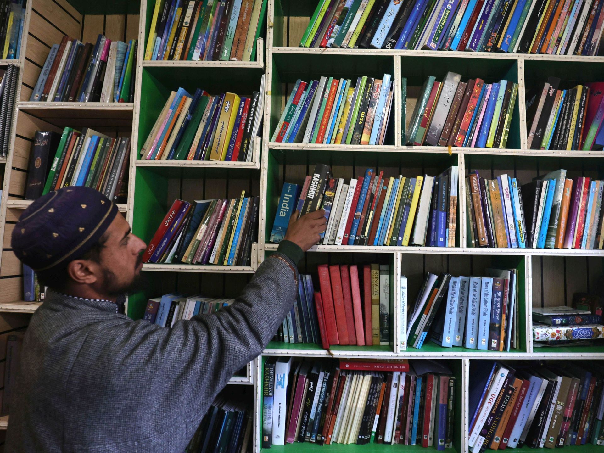 Um homem lê um livro dentro de uma biblioteca em Srinagar, 17 de fevereiro de 2025