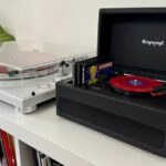 o pequeno player de vinil, a caixa e o expositor em um console de mídia branco