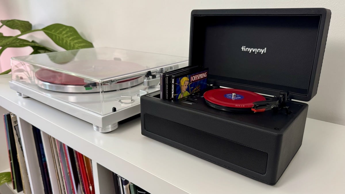 o pequeno player de vinil, a caixa e o expositor em um console de mídia branco