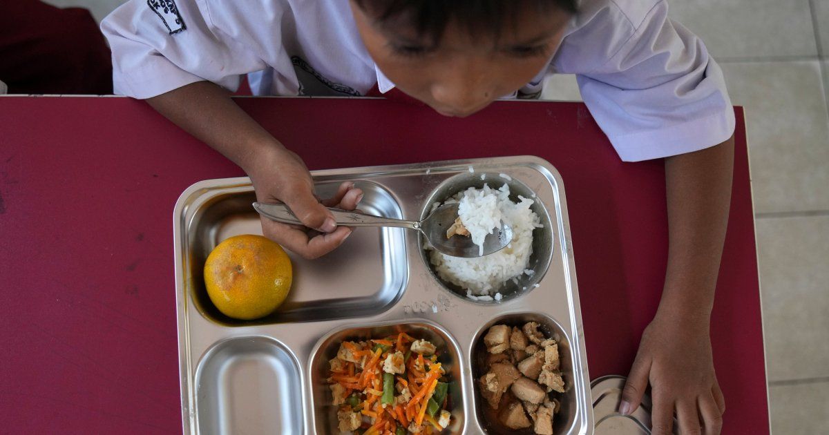 Membros do comitê escolar distribuem refeições aos alunos durante o lançamento do ambicioso programa de refeições gratuitas do presidente Prabowo Subianto para alimentar crianças e mulheres grávidas em todo o país, apesar dos críticos dizerem que a logística necessária poderia prejudicar as finanças e a economia do estado da Indonésia, em uma escola primária em Depok, Java Ocidental, Indonésia, segunda-feira, 6 de janeiro de 2025. (AP Photo/Dita Alangkara)