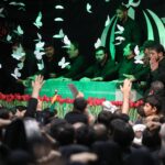 Um homem passa de scooter por um outdoor com imagens do falecido fundador da Revolução Islâmica, líder supremo, aiatolá Ruhollah Khomeini (L), do líder supremo do Irã, Ali Khamenei (C), e de seu filho, o atual líder supremo, Mojtaba Khamenei, ao longo da rua em Teerã, em 3 de julho de 2026. Os preparativos para o funeral do líder supremo do Irã, Ali Khamenei, estavam a todo vapor em 3 de julho, com as autoridades esperam que milhões e um círculo de dignitários estrangeiros compareçam à cerimónia oficial. (Foto de ATTA KENARE/AFP)/