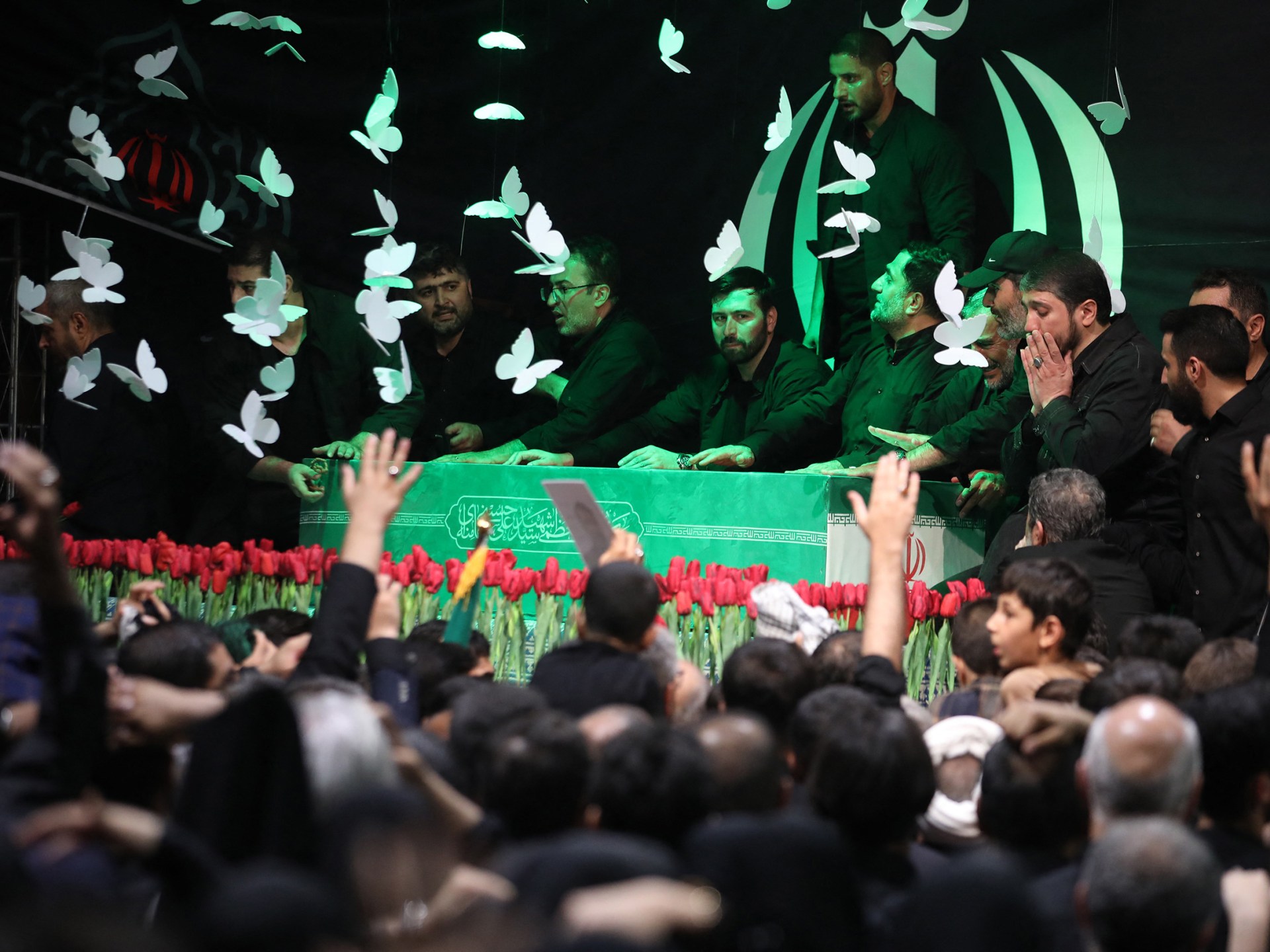 Um homem passa de scooter por um outdoor com imagens do falecido fundador da Revolução Islâmica, líder supremo, aiatolá Ruhollah Khomeini (L), do líder supremo do Irã, Ali Khamenei (C), e de seu filho, o atual líder supremo, Mojtaba Khamenei, ao longo da rua em Teerã, em 3 de julho de 2026. Os preparativos para o funeral do líder supremo do Irã, Ali Khamenei, estavam a todo vapor em 3 de julho, com as autoridades esperam que milhões e um círculo de dignitários estrangeiros compareçam à cerimónia oficial. (Foto de ATTA KENARE/AFP)/