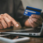 Pessoa que usa um cartão de crédito para fazer um pagamento on-line em um laptop, ilustrando o processamento de pagamentos digitais e transações de jogos de azar on-line. Reclamação da EGBA visa Walletto sobre pagamentos ilegais de jogos de azar na Lituânia