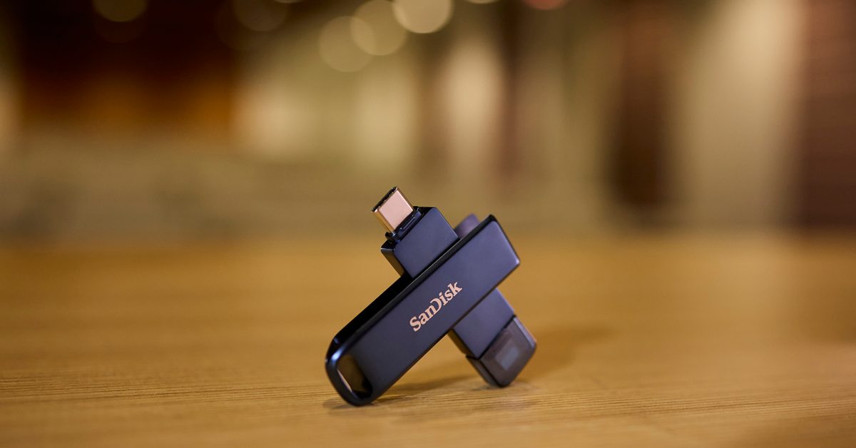 SANDISK Phone Drive para iPhone mostrado em uma mesa com iluminação fora de foco atrás
