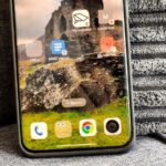 Uma mão organizando aplicativos na tela de um smartphone, cercada por vários ícones coloridos de aplicativos