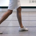 Quatro homens vestindo shorts no escritório em Tóquio, Japão. Três deles em pé, um deles sentado e com os cotovelos apoiados na mesa.