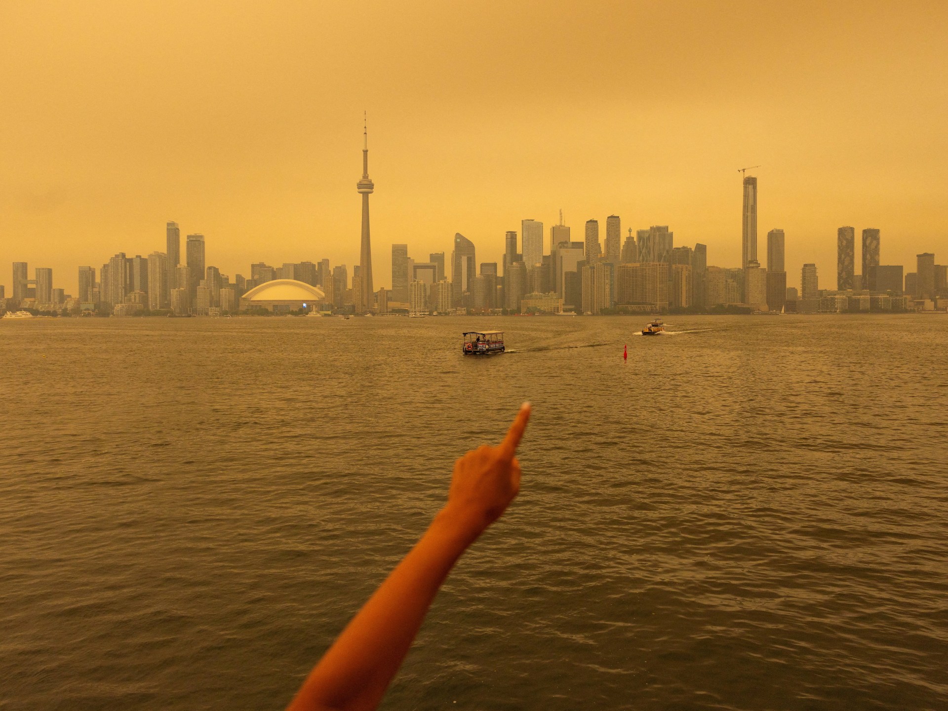Uma pessoa coloca uma máscara refletida no espelho de uma loja de souvenirs, enquanto a fumaça do incêndio florestal do noroeste de Ontário enche o céu, em Toronto na quarta-feira