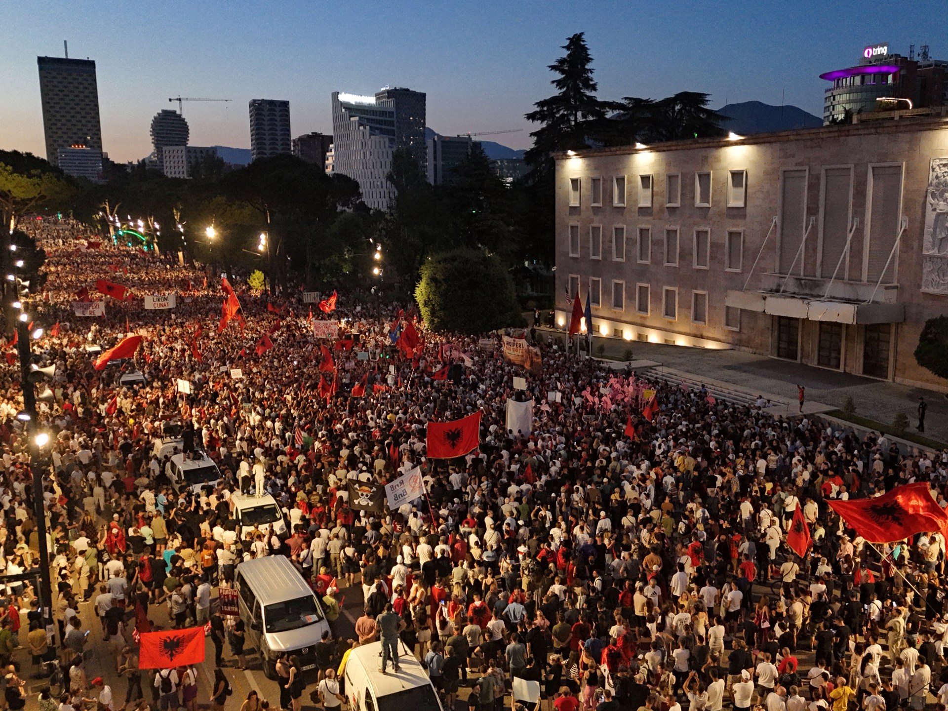 Manifestantes carregam cartazes enquanto se manifestam em frente ao Gabinete do Primeiro Ministro albanês contra a construção de um resort de luxo perto de uma área natural protegida na costa sul da Albânia, em Tirana, em 4 de julho de 2026.