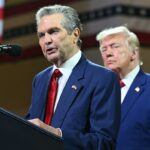 President Donald Trump, background, looks on as Republican gubernatorial candidate Rick Jackson speaks at Wheeler High School in Marietta, Georgia, on July 22. (Photo by Saul Loeb/AFP via Getty Images)