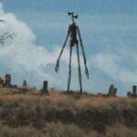 Um monstro alto é visível no horizonte ao anoitecer.